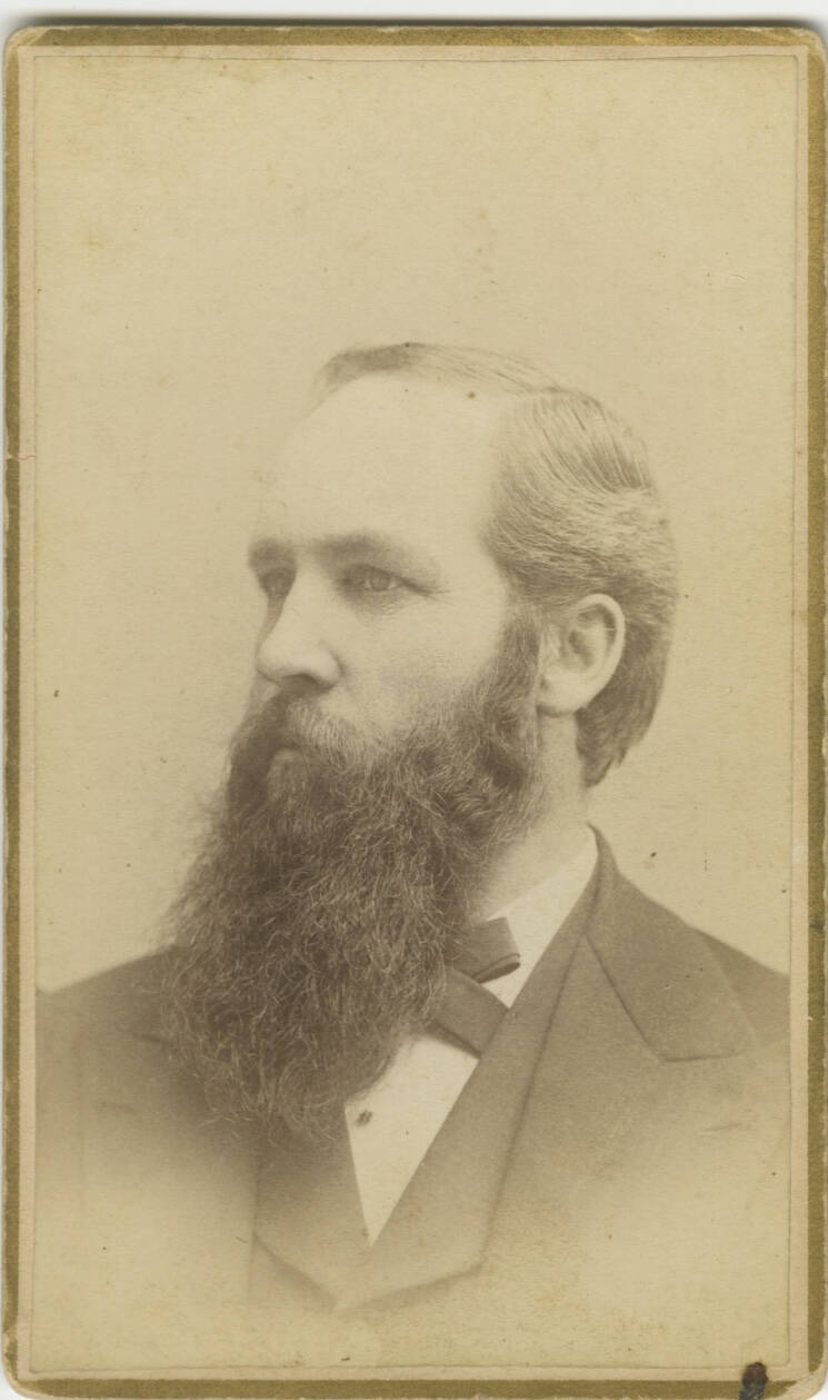Historic studio portrait photograph of a man, looking to the side, with a long beard.